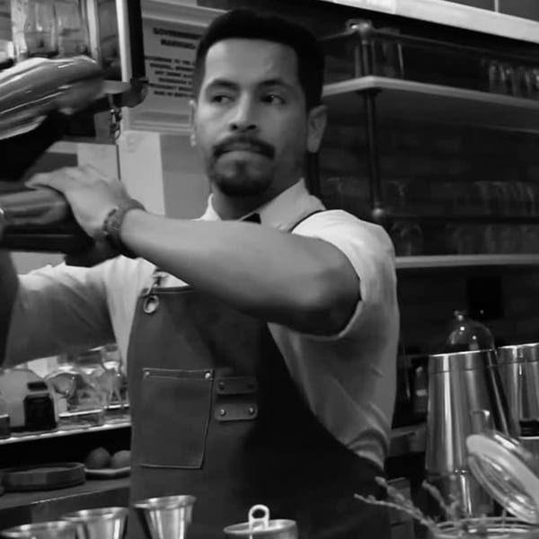 Bartender in an apron shaking a cocktail mixer at Frida's Mexican Cuisine.
